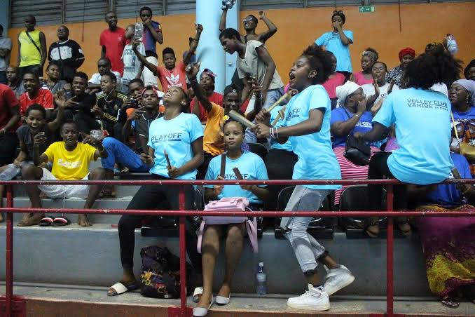 Supporters de volley en t-shirts bleus qui chantent dans les gradins